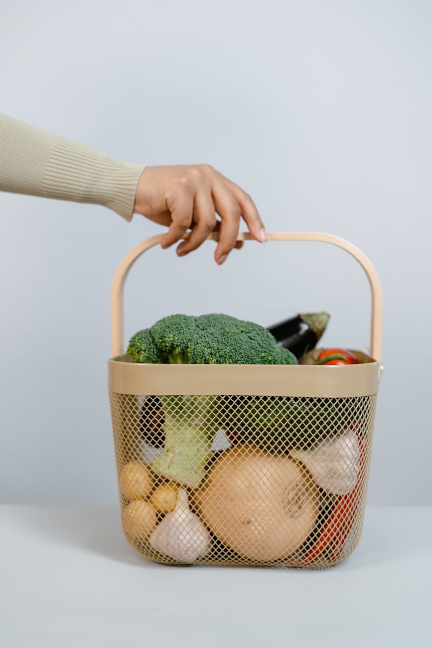 a person holding a basket with fruits and vegetables